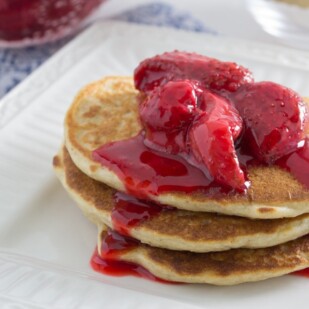 Juice laden roasted strawberries over Low FODMAP protein packed fluffy Quinoa Pancakes.