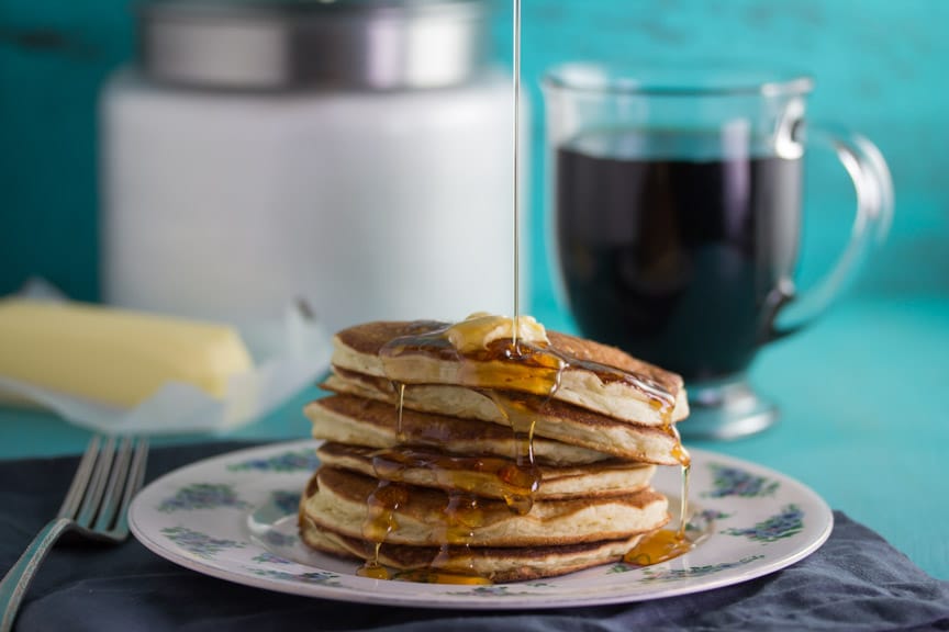 Low FODMAP Buttermilk Oat Pancakes stacked on a decorative plate with syrup poured on top