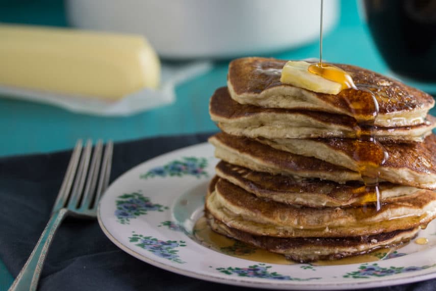  Stack of Low FODMAP Buttermilk Oat Pancakes with butter and syrup being poured over the top