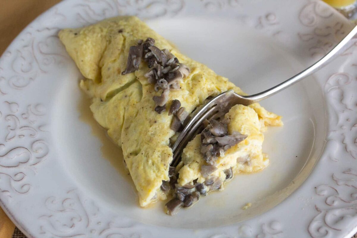 fork cutting into a low FODMAP mushroom omelet on white plate
