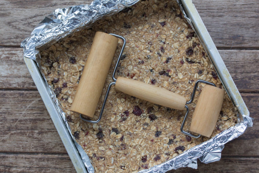 Use a double roller to flatten out these soft granola bars in the pan. 