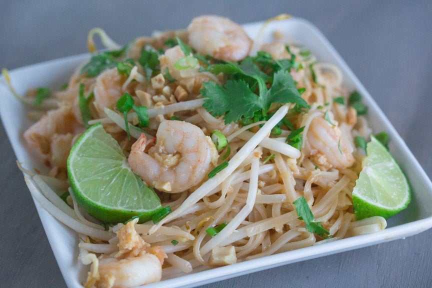 Low FODMAP Pad Thai served with limes on a plate. 