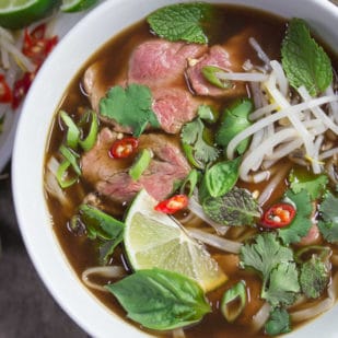 A bright bowl full of Low FODMAP Pho Bo (Vietnamese Beef Noodle Soup) - beautiful, comforting and delicious.