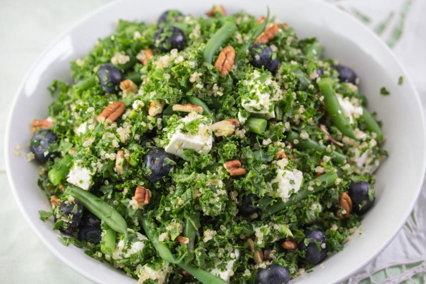 Low FODMAP kale blueberry feta salad tossed together in a bowl makes for a delicious and festive addition to any meal