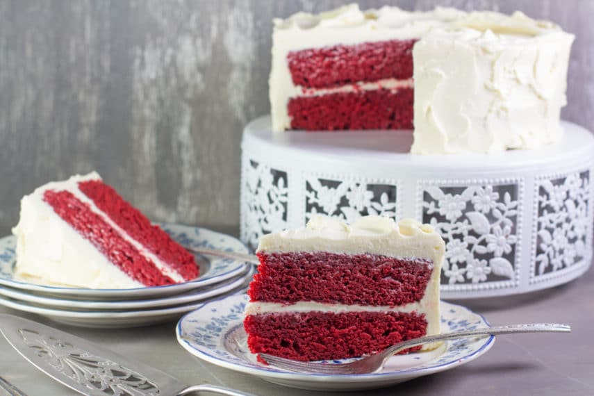 Beautiful slices of low FODMAP Red Velvet Cake on a decorative white stand