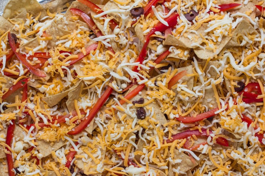 The base layer of our Low FODMAP Salad Nachos - corn chips, cheese, olives, red peppers - ready to go into the oven. 