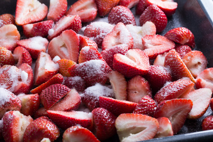 Sliced fresh strawberries tossed in sugar, ready to be roasted. 
