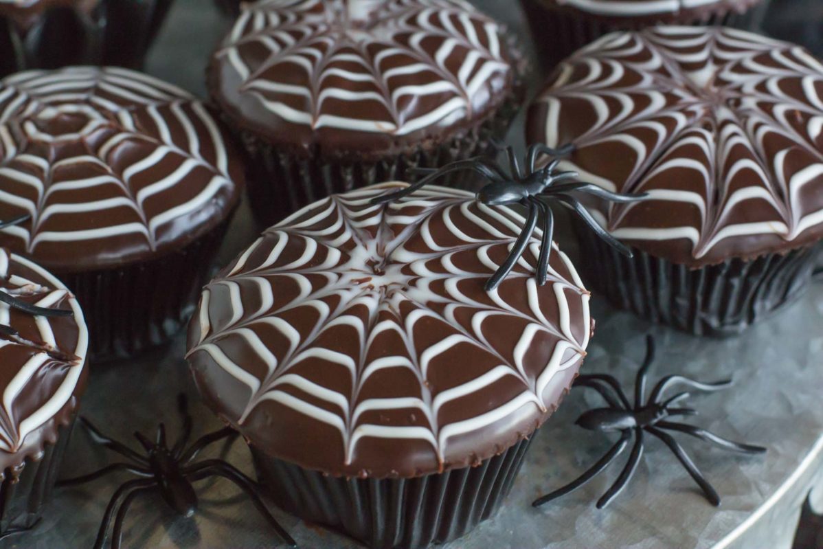 A close up view of spiderweb decorated chocolate cupcakes.