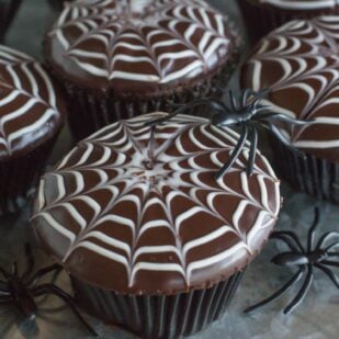 A close up view of spiderweb decorated chocolate cupcakes.