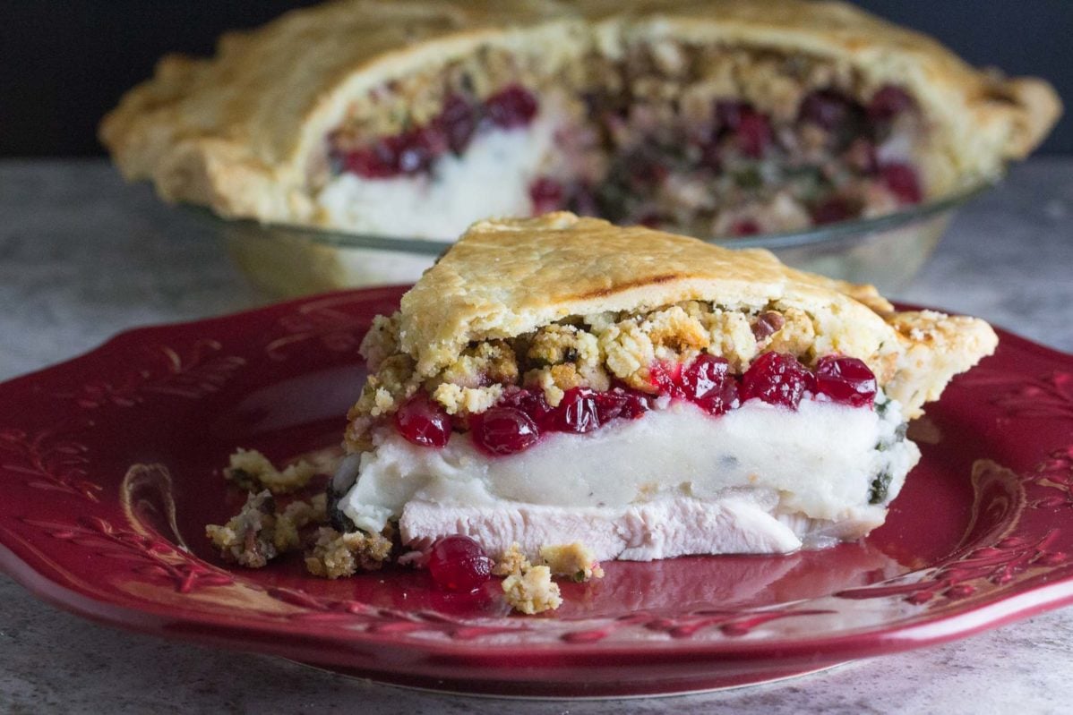 Slice of Thanksgiving Leftover Pie on a burgundy plate. Whole pie in background