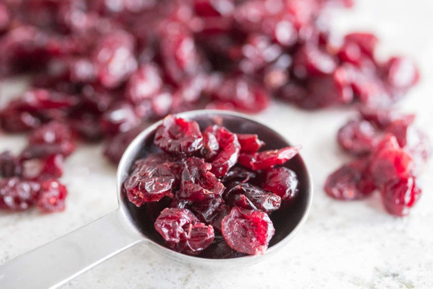 dried cranberries in a tablespoon on a white and gray background