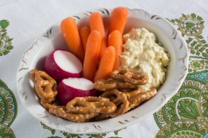 Egg salad with baby carrots, radishes and gluten free pretzels in an oval dish