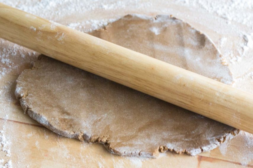 gingerbread dough being rolled out with wooden rolling pin