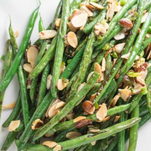 pan-roasted green beans topped with toasted almonds on an oval white platter