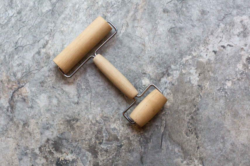 hand held wooden rolling pin on a stone backdrop