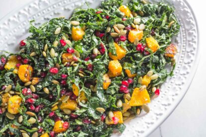 kale salad with butternut squash and pomegranate on serving platter for the table