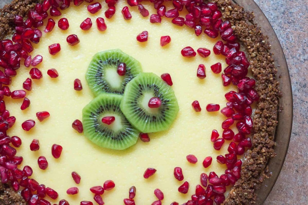lactose free cheesecake pie in a pat-in crust topped with pomegranate and kiwi