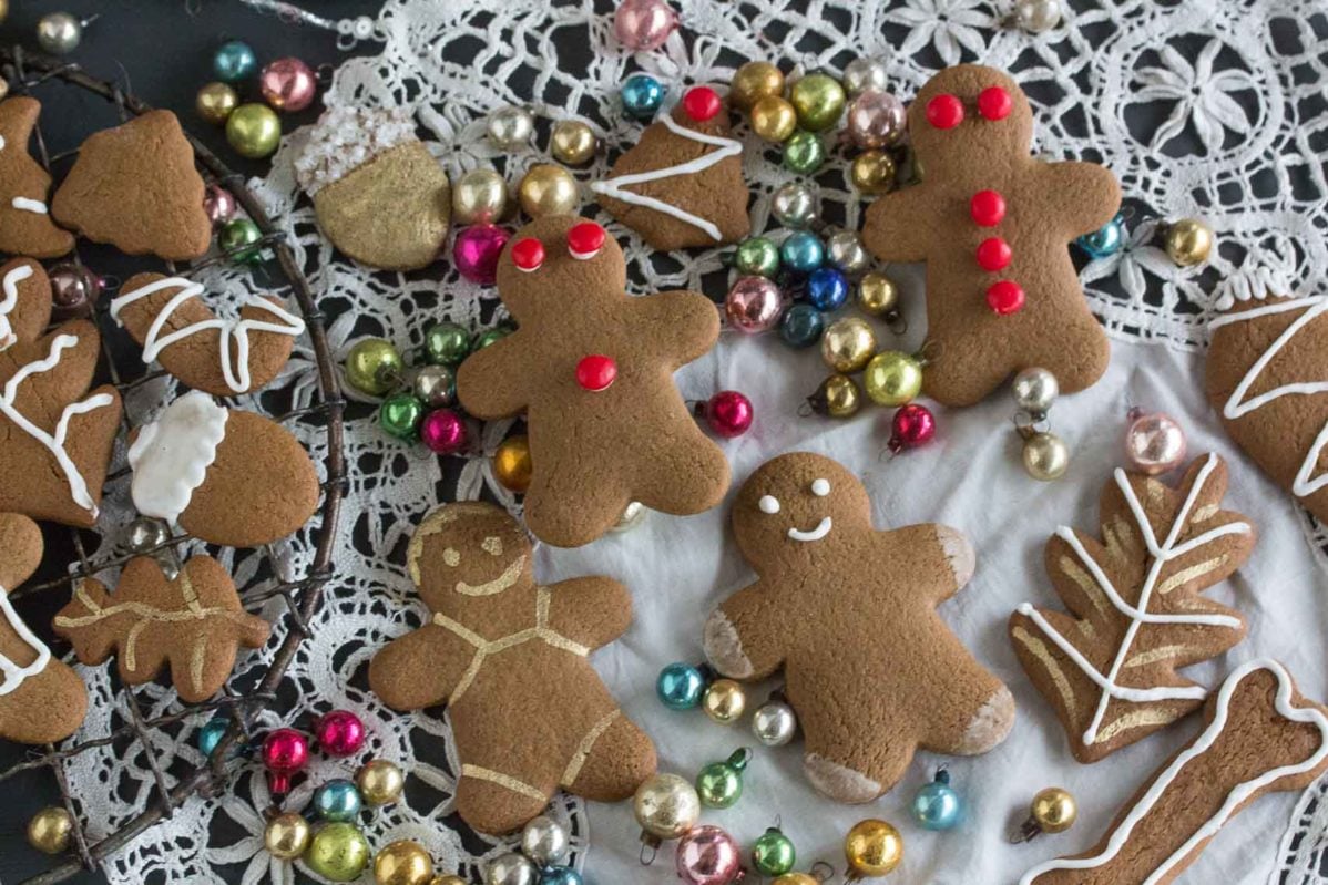 overhead shot of gingerbread cookies decorated with red hot candies and icing and edible gold paint on an antique clot