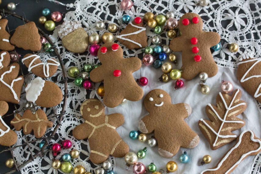 gingerbread cookies decorated with red hot candies and icing and edible gold paint on an antique cloth. Gluten-Free Christmas Cookies everyone will love