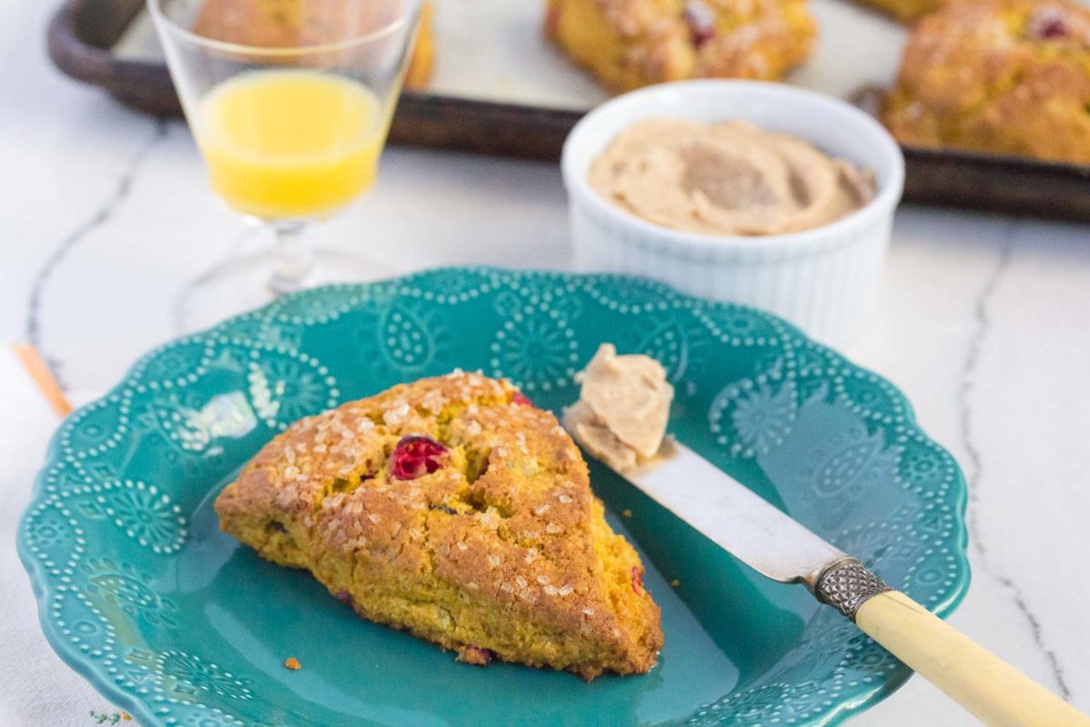 pumpkin cranberry scones with cinnamon butter in a ramekin, served with a glass of orange juice