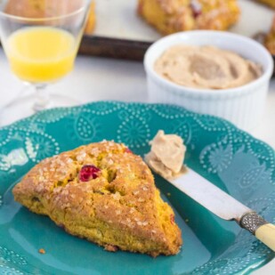 pumpkin cranberry scones with cinnamon butter in a ramekin, served with a glass of orange juice