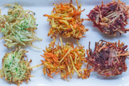 three kinds of vegetable latkes: zucchini, carrot and beet on a white plate