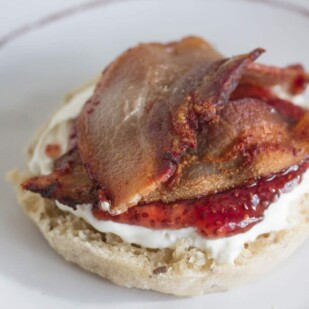 English muffin spread with lactose-free cream cheese, topped with raspberry chia jam and crisp bacon