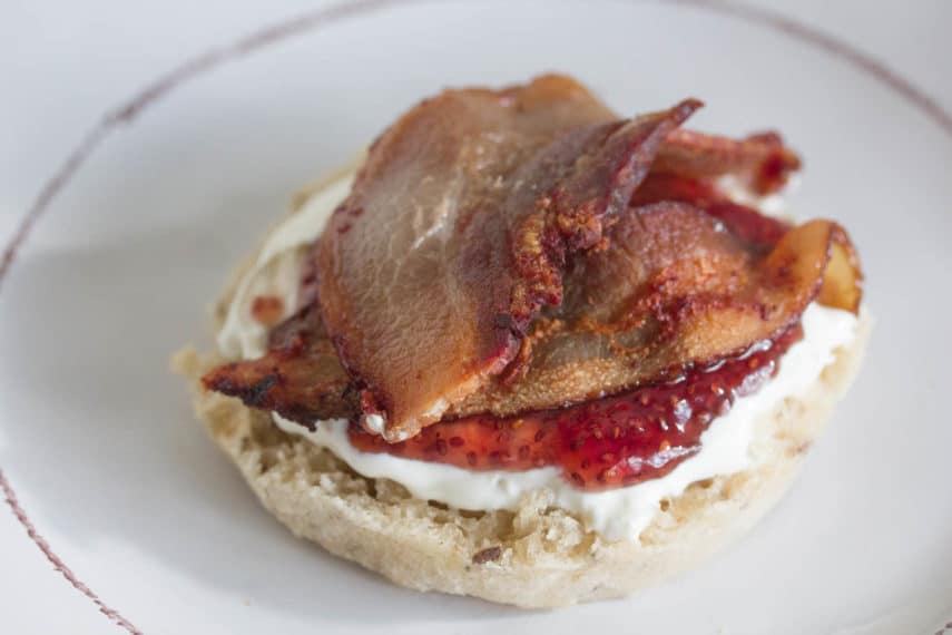 English muffin spread with lactose-free cream cheese, topped with raspberry chia jam and crisp bacon