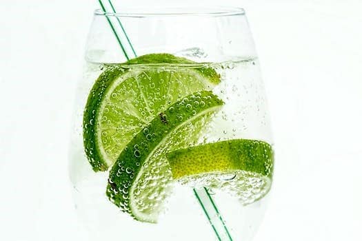 Gin Ricky Cocktail with three limes and a straw in a glass. 