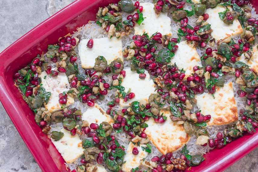 Baked Rice with Olives, Feta & Pomegranate in a red baking dish
