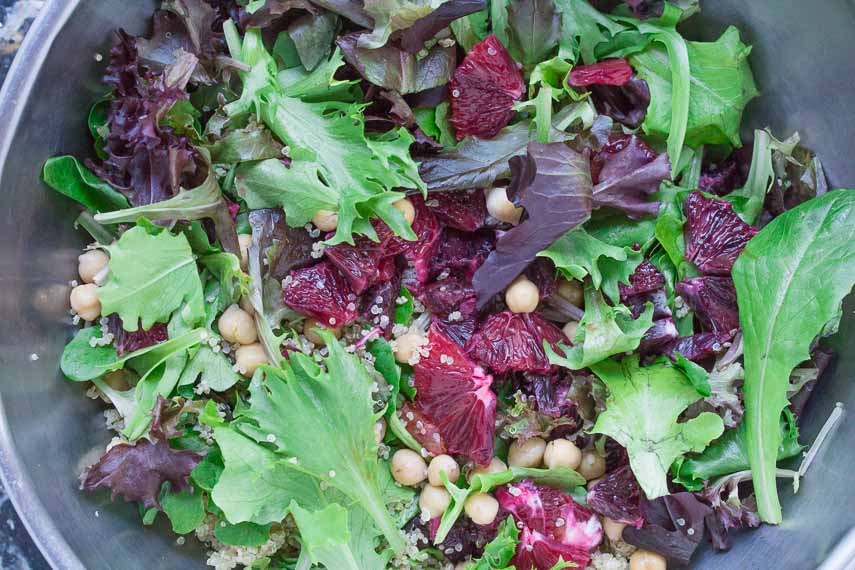tossing togetther Grains & Greens: Baby Lettuces, Blood Oranges, Quinoa & Chickpeas in a bowl