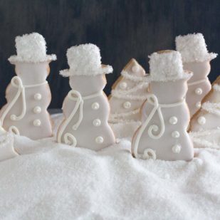 decorated sugar cookies in a white Christmas theme in a snow bank of sugar