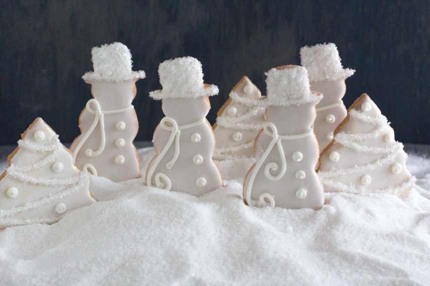 decorated sugar cookies in a white Christmas theme in a snow bank of sugar