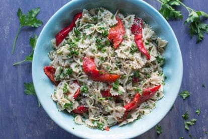 farfalle with roasted red peppers and parsley in a blue bowl overhead shot