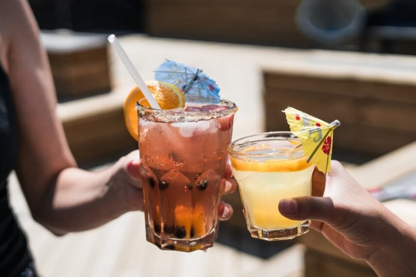 A cheers between two iced drinks with umbrellas 