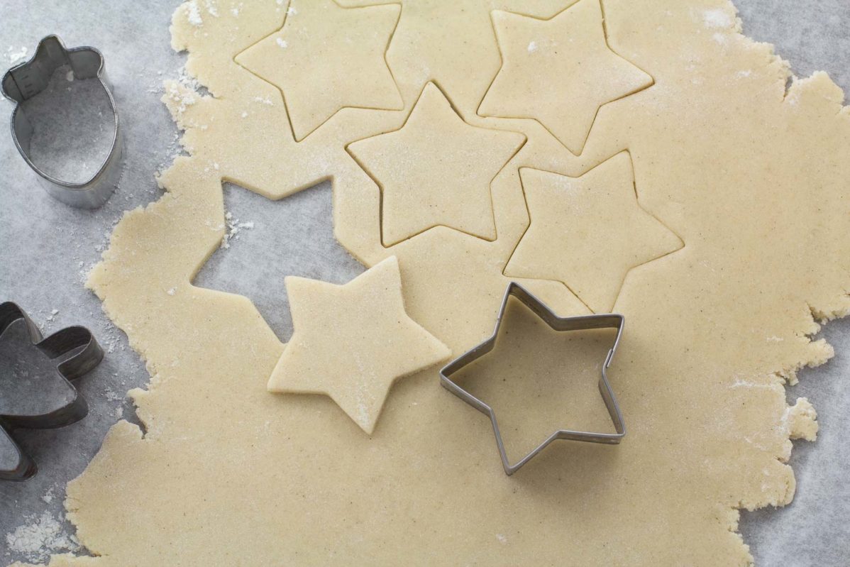 raw rolled sugar cookie dough rolled out with star cookie cutter