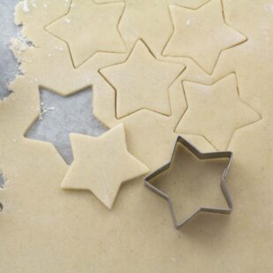 raw rolled sugar cookie dough rolled out with star cookie cutter
