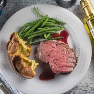 overhead shot of standing rib roast on white plate with popovers, green beans and FODY products