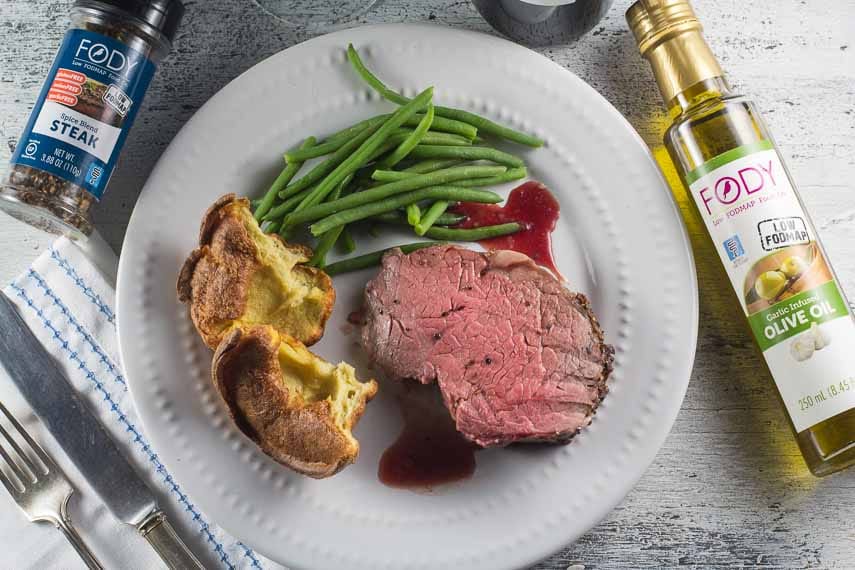 overhead shot of standing rib roast on white plate with popovers, green beans and FODY products