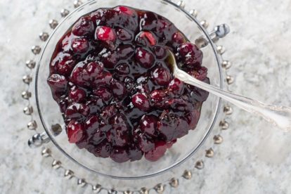 savory cranberry sauce in a glass dish with a silver spoon