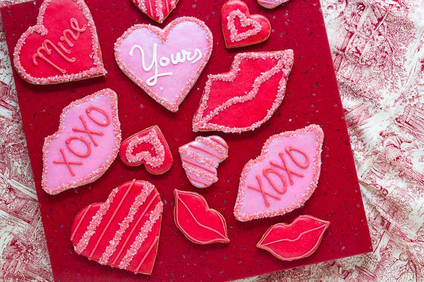 Low FODMAP, gluten-free Valentine's Day cookies, overhead shot, on red quartz square and red and white fabric