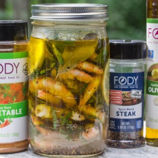 Low FODMAP Pickled Shrimp in a glass jar with ingredients alongside