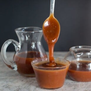 salted caramel sauce pouring from spoon against a black background