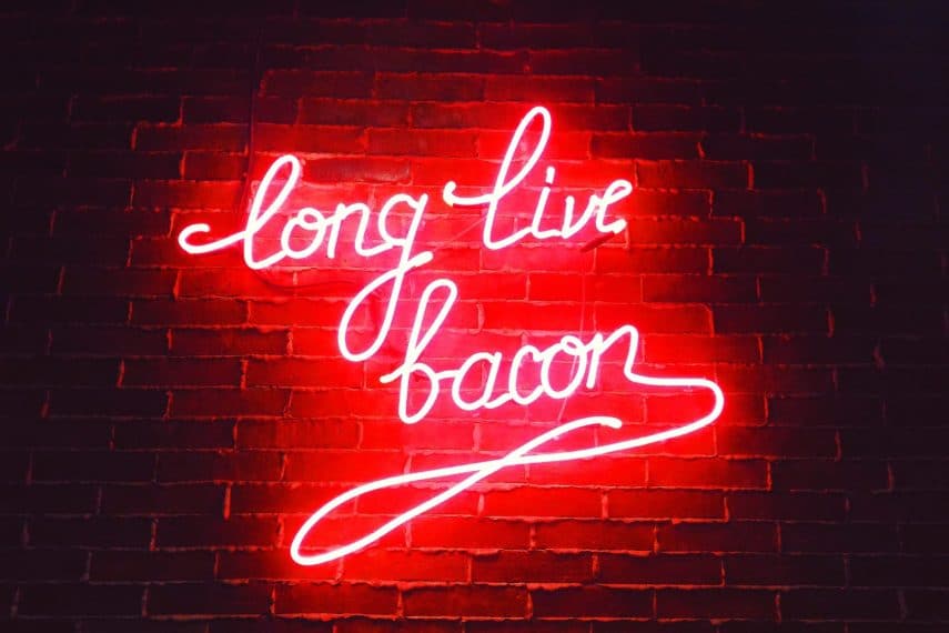 Red neon sign saying Long Live Bacon against a brick wall.