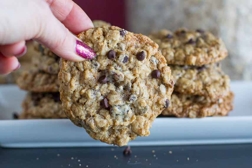 oatmeal chocolate chip cookies; hand removing one from white platter