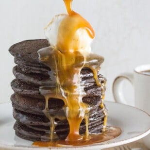 tall stack of chocolate pancakes with lactose free vanilla ice cream and salted caramel sauce