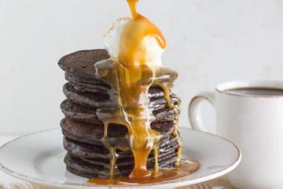 tall stack of chocolate pancakes with lactose free vanilla ice cream and salted caramel sauce
