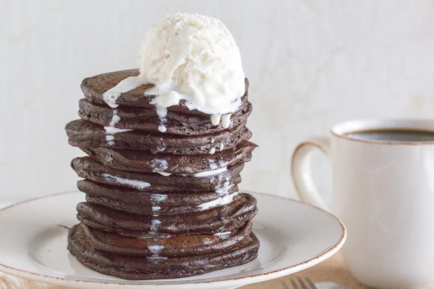 tall stack of chocolate pancakes with melting vanilla oce c ream on top