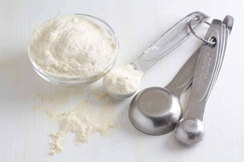 Powdered xantham gum in bowl and measuring spoon. 