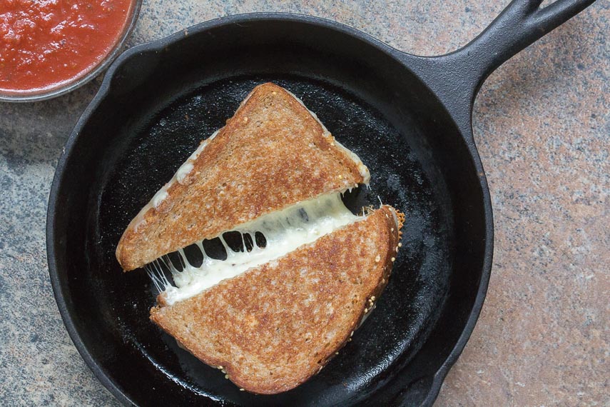 grilled cheese in cast iron pan with cheese oozing out, salsa on the side